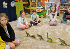 dzieci układają dinozaury w jednym rzędzie
