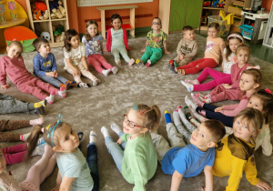 Dzieci siedzą w kole i prezentują swoje kolorowe skarpetki