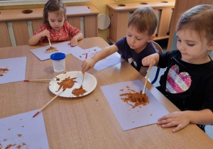 Dzieci malują przy stoliku misie z masy gipsowej