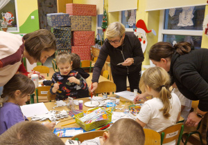 Dzieci wspólnie z rodzicami wykonują bożonarodzeniowe ozdoby