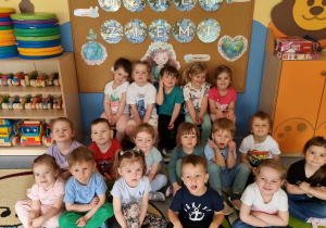 Dzieci siedzą na tle dekoracji z okazji Dnia Ziemi