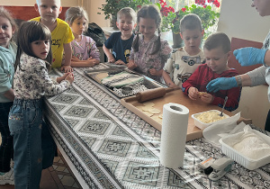 Przedszkolaki lepią pierogi z twarogiem.