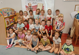 Dzieci stoją na tle dekoracji "Narodowe Czytanie 2025"