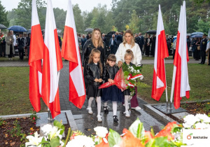 Dzieci składają kwiaty pod pomnikiem
