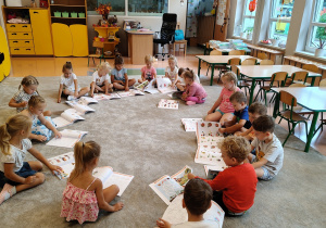 dzieci na dywanie oglądają karty pracy