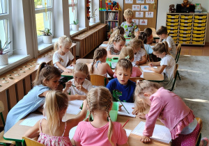 dzieci wykonują kodowanie przy stolikach