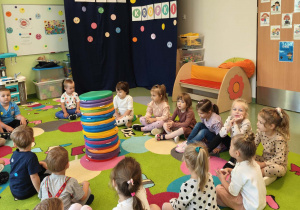 Dzieci siedzą na dywanie w kole