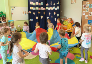 Dzieci uczestniczą w zabawie z chustą animacyjną