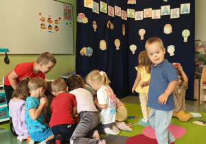 Dzieci na dywanie chodzą ścieżką sensoryczną oraz bawią się zabawkami