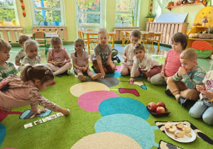 Dzieci siedzą na dywanie podczas zajęć dydaktycznych i wykonują ćwiczenia