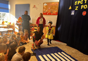 Policjantka pokazuje dzieciom sygnalizator świetlny.