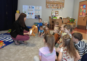 Policjantka pokazuje młodszym dzieciom jak reagować , gdy zbliża się do nich pies.