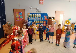 Dzieci stoją w kółku i pokazują układ do muzyki.