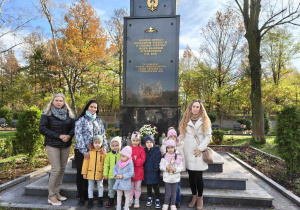 Dzieci, wychowawca i pomoce na tle pomnika