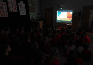 Dzieci oglądają film edukacyjny na tablicy interaktywnej