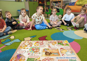 Dzieci siedzą w kole na dywanie i słuchają o prawach dziecka