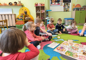 Dzieci siedzą w kole na dywanie i słuchają o prawach dziecka
