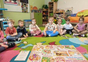 Dzieci siedzą w kole na dywanie i słuchają o prawach dziecka