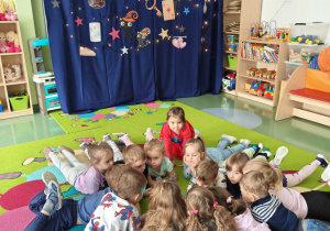 Dzieci leżą na dywanie i przyglądają się świecącej kuli