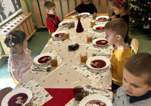 Dzieci siedzą przy wigilijnym stole