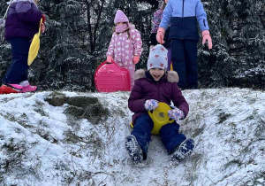 Dzieci zjeżdzaja z górki.