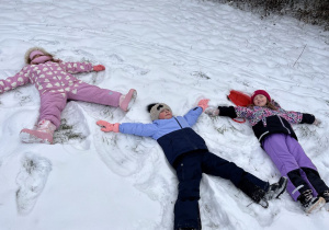 Dziewczynki robią aniołki na śniegu.