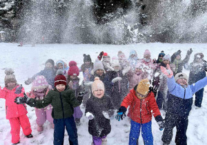 Dzieci wyrzucają śnieg do góry.