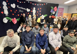 Dziadkowie siedzą na krzesłach w kapeluszach