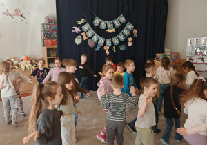 Dzieci chodzą po sali i udają dinozaury