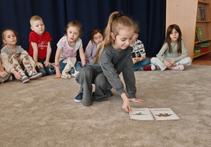 Dziewczynka układa karty na dywanie