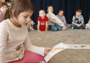 Dziewczynka czyta nazwę dinozaura