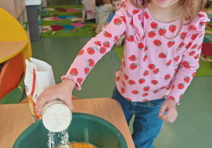 dziewczynka wsypuje mąkę do miski