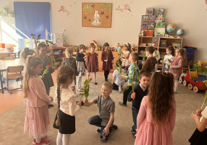 Chłopcy wręczają kwiaty dziewczynkom.