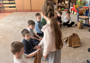 Dziewczynka rozdaje upominki dla chlopców .